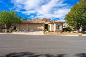 Mediterranean / spanish ranch style house featuring an attached garage, stucco siding, concrete driveway, and a tile roof