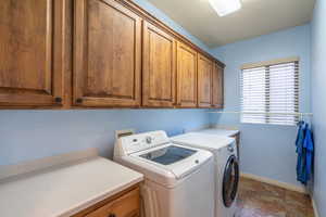 Laundry room with washing machine and clothes dryer, folding table and cabinetry