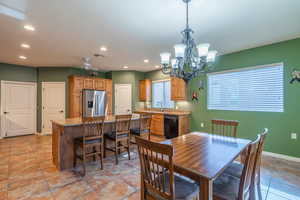 View of kitchen and dining area with under cabinet lighting, fan in kitchen, chandeler above dining table, and recessed lighting. Wood finish and tile flooring.