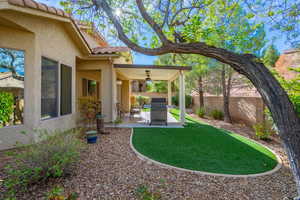 Fenced backyard with a patio and a ceiling fan and lots of shade