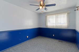 Carpeted spare room with a textured ceiling and a ceiling fan
