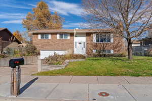 Raised ranch featuring brick siding, concrete driveway, and a garage