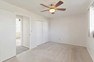 Primary  bedroom with light colored carpet, ceiling fan, and a closet