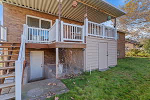 View of side of home featuring brick siding, a lawn, and a wooden deck, shed under deck