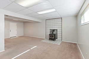 Family room with a wood stove, carpet, and a paneled ceiling