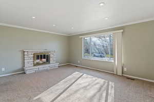 Unfurnished living room with ornamental molding, carpet, a fireplace, and recessed lighting