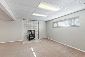 Unfurnished Family room with a wood stove, carpet, and a drop ceiling