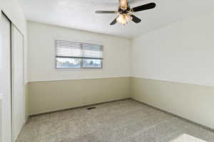 Unfurnished bedroom featuring a closet, ceiling fan, a textured ceiling, and light colored carpet
