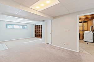 Below grade area with a paneled ceiling, washer / clothes dryer, and carpet