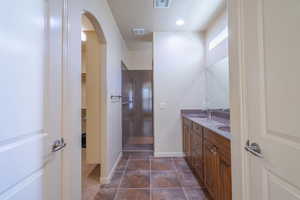 Bathroom featuring double vanity, a walk in closet, dark tile patterned flooring, and a walk in shower