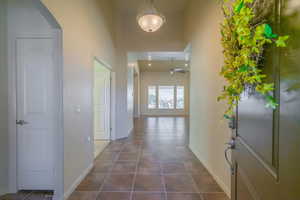 Hall with dark tile patterned floors, a high ceiling, and arched walkways