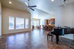 Living area with a ceiling fan, vaulted ceiling, dark tile patterned floors, a textured ceiling, and recessed lighting