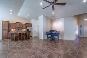 Kitchen featuring a center island with sink, a kitchen bar, a textured ceiling, decorative backsplash, and appliances with stainless steel finishes