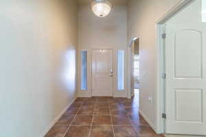 Foyer featuring arched walkways, dark tile patterned flooring, and a high ceiling