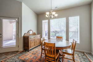Dining space featuring plenty of natural light, a chandelier, vaulted ceiling, and light tile patterned floors