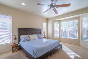 Primary Bedroom with bay windows, light colored carpet, recessed lighting, and ceiling fan