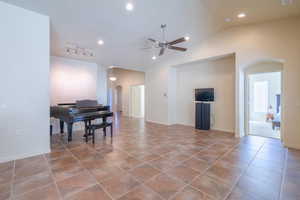 Living area featuring arched walkways, ceiling fan, light tile patterned floors, vaulted ceiling, and recessed lighting