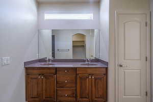 Full bath with double vanity, plenty of natural light, and a textured wall
