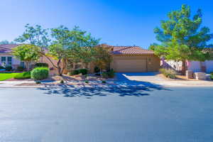 View of front of house featuring concrete driveway, an attached garage, stucco siding, and a tiled roof