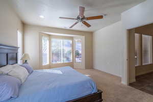 Carpeted bedroom with ceiling fan and a textured ceiling