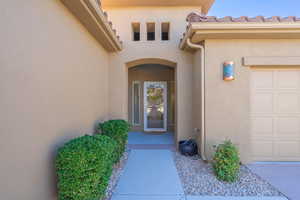 Doorway to property featuring stucco siding and an attached garage