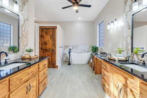Full bath with double vanity, two vanities, tile walls, a freestanding tub, and recessed lighting