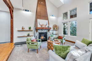 Living area with a fireplace, a high ceiling, and wood finished floors