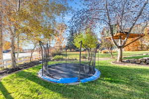 View of grassy yard featuring a trampoline