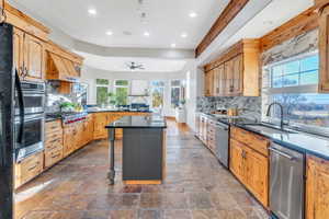 Kitchen featuring backsplash, a kitchen island, stone tile floors, dark stone countertops, and a breakfast bar area