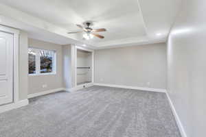 Unfurnished bedroom featuring light carpet, a ceiling fan, and a raised ceiling