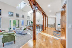 Living area with light wood-type flooring, healthy amount of natural light, a skylight, recessed lighting, and a towering ceiling