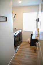 Washroom with dark wood-type flooring, washing machine and dryer, and recessed lighting