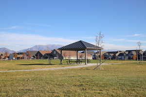 View of jungle gym featuring a lawn, a patio, a residential view, and a mountain view