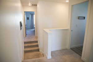 Hallway featuring light carpet and stairway