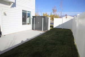 Fenced backyard with a storage unit and a patio area