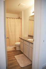 Full bath featuring curtained shower, dark wood finished floors, and vanity