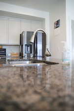 Kitchen view of dark stone counters and white cabinetry