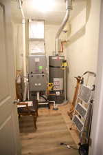 Utility room featuring strapped water heater and heating unit