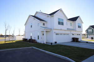 View of home's exterior with board and batten siding, driveway, a garage, a metal roof, and a standing seam roof