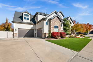 Craftsman-style home featuring stone siding, stucco siding, driveway, and a gate
