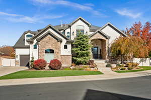 French provincial home with stone siding, stucco siding, a garage, and concrete driveway