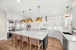 Kitchen featuring white cabinets, light stone countertops, pendant lighting, light wood-style flooring, and recessed lighting