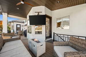 Wooden terrace featuring a ceiling fan and an outdoor living space with a fire pit
