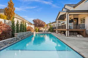 View of swimming pool with a patio area, a fenced backyard, a residential view, a wooden deck, and stairs
