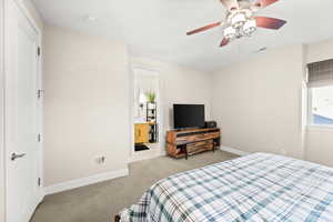 Bedroom with carpet floors, ceiling fan, and ensuite bath