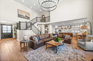 Living room featuring a chandelier, ornamental molding, hardwood / wood-style flooring, recessed lighting, and stairway