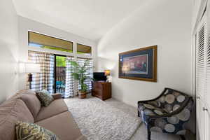 Living area featuring carpet and vaulted ceiling
