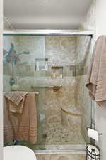 Bathroom featuring a shower stall and a textured ceiling