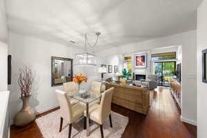 Dining room with a fireplace, dark wood-style floors, and a textured ceiling