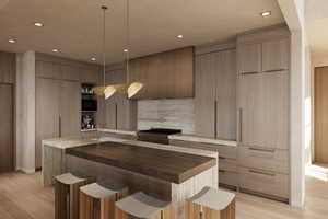 Kitchen featuring modern cabinets, wood counters, a breakfast bar, a kitchen island with sink, and recessed lighting